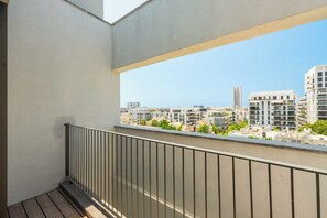A balcony with a metal railing overlooking a cityscape with modern buildings. - Bright Stay • Private Skyline Balcony by SeaNRent (Tel-Aviv)