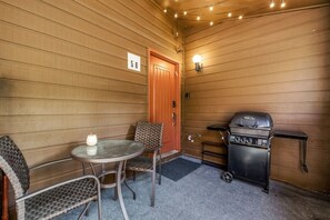 A room with a wooden door, a table with chairs, a barbecue grill, and a number sign on the wall. - EagleVail Retreat | Near Vail & Beaver Creek (Avon)