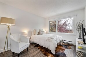 A bedroom with a bed, a chair, a lamp, a window, and a radiator. - EagleVail Retreat | Near Vail & Beaver Creek (Avon)