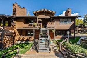 A modern two-story building with a wooden exterior, a central staircase, and outdoor seating areas. - EagleVail Retreat | Near Vail & Beaver Creek (Avon)