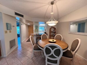 A dining area with a round table, six chairs, and a pendant light. - Indies House Condo on the Beach! UNIT 105 - 2-bedroom, 2 bathroom condo! (Ormond Beach)