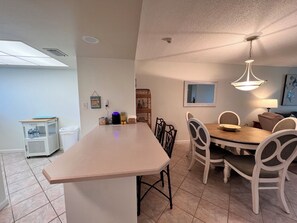 Uma cozinha moderna com ilha central, mesa de jantar e cadeiras.