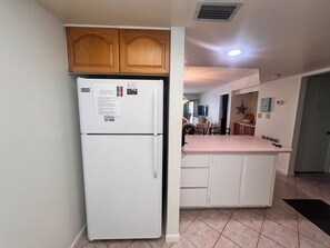 A compact kitchen with a white refrigerator, wooden cabinets, and a small countertop. - Indies House Condo on the Beach! UNIT 105 - 2-bedroom, 2 bathroom condo! (Ormond Beach)