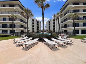 A resort with a central pool, multiple balconies, and sun loungers. - Indies House Condo on the Beach! UNIT 105 - 2-bedroom, 2 bathroom condo! (Ormond Beach)