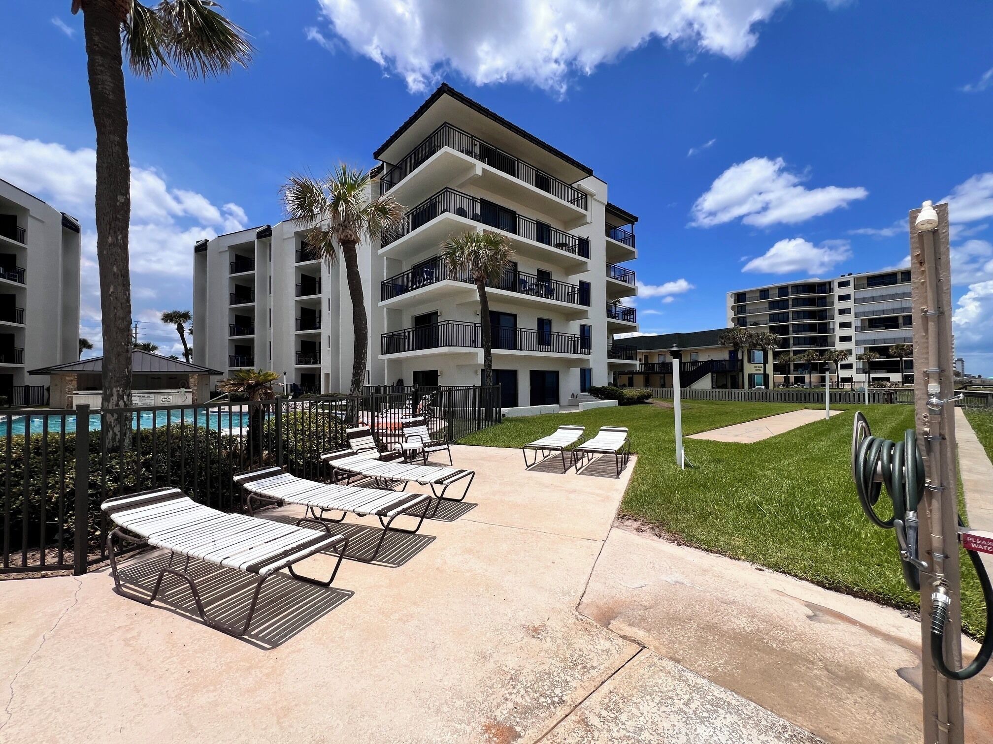 Um hotel com área de piscina, mobiliário de exterior e céu limpo.