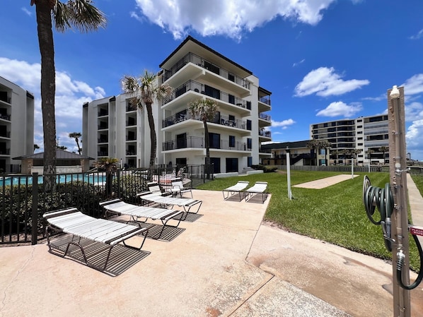 A hotel with a pool area, outdoor seating, and a clear sky. - Indies House Condo on the Beach! UNIT 105 - 2-bedroom, 2 bathroom condo! (Ormond Beach)