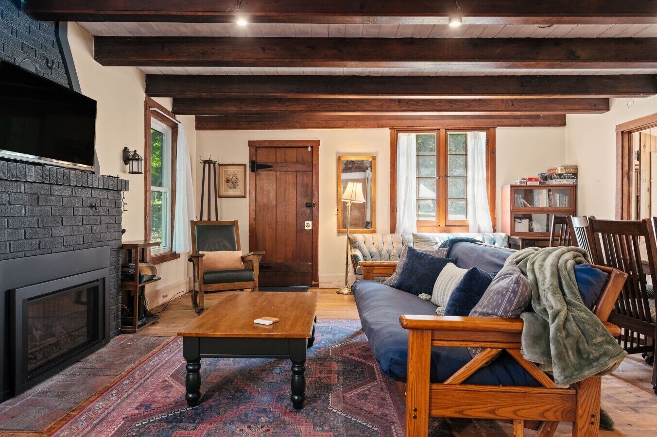 A cozy living room with a fireplace, a sofa, a coffee table, and a bookshelf.