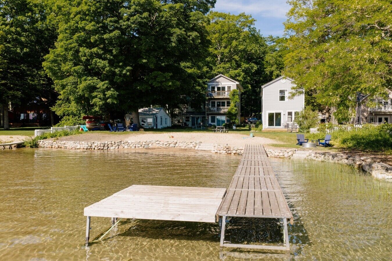 Een houten steiger die zich uitstrekt over een rustig waterlichaam, omgeven door weelderige begroeiing en woongebouwen.