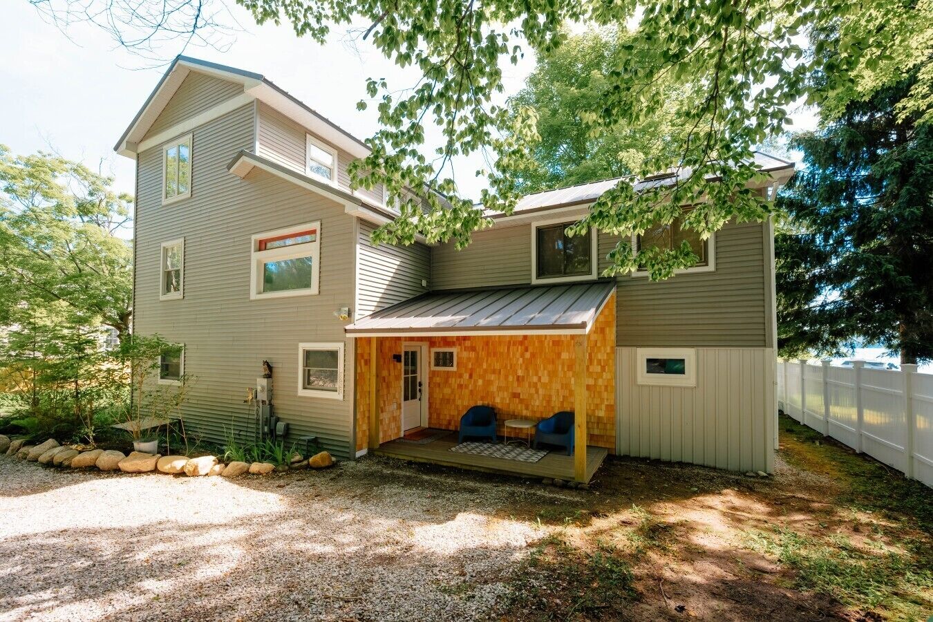 A two-story house with a covered porch and a small deck area.