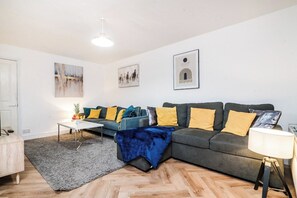 A living room with a sofa, coffee table, and artwork on the wall. - Bold & Cosy 3BDR | Family Home | Parking | Wi-Fi (Tividale)