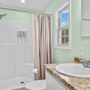 A bathroom with a shower, toilet, and sink.