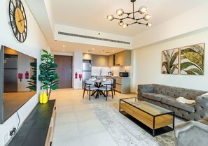 A modern living room with a sofa, coffee table, and dining area. - 1BR Umm Suqiem Apartment w/ Burj Al Arab Pool View, Steps to Kite Beach (Dubai)