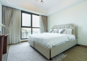 A modern bedroom with a large bed, a desk, and a view of the city through a large window. - 1BR Umm Suqiem Apartment w/ Burj Al Arab Pool View, Steps to Kite Beach (Dubai)