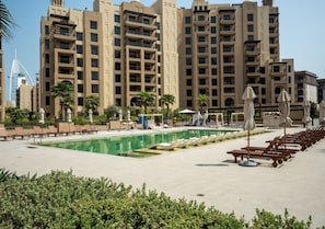 A hotel pool area with sun loungers and umbrellas, surrounded by high-rise buildings. - 1BR Umm Suqiem Apartment w/ Burj Al Arab Pool View, Steps to Kite Beach (Dubai)