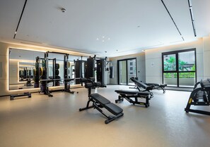 Ein modernes Fitnessstudio mit Gewehrscheiben, Bänken und einem großen Spiegel, der den Raum widerspiegelt.
