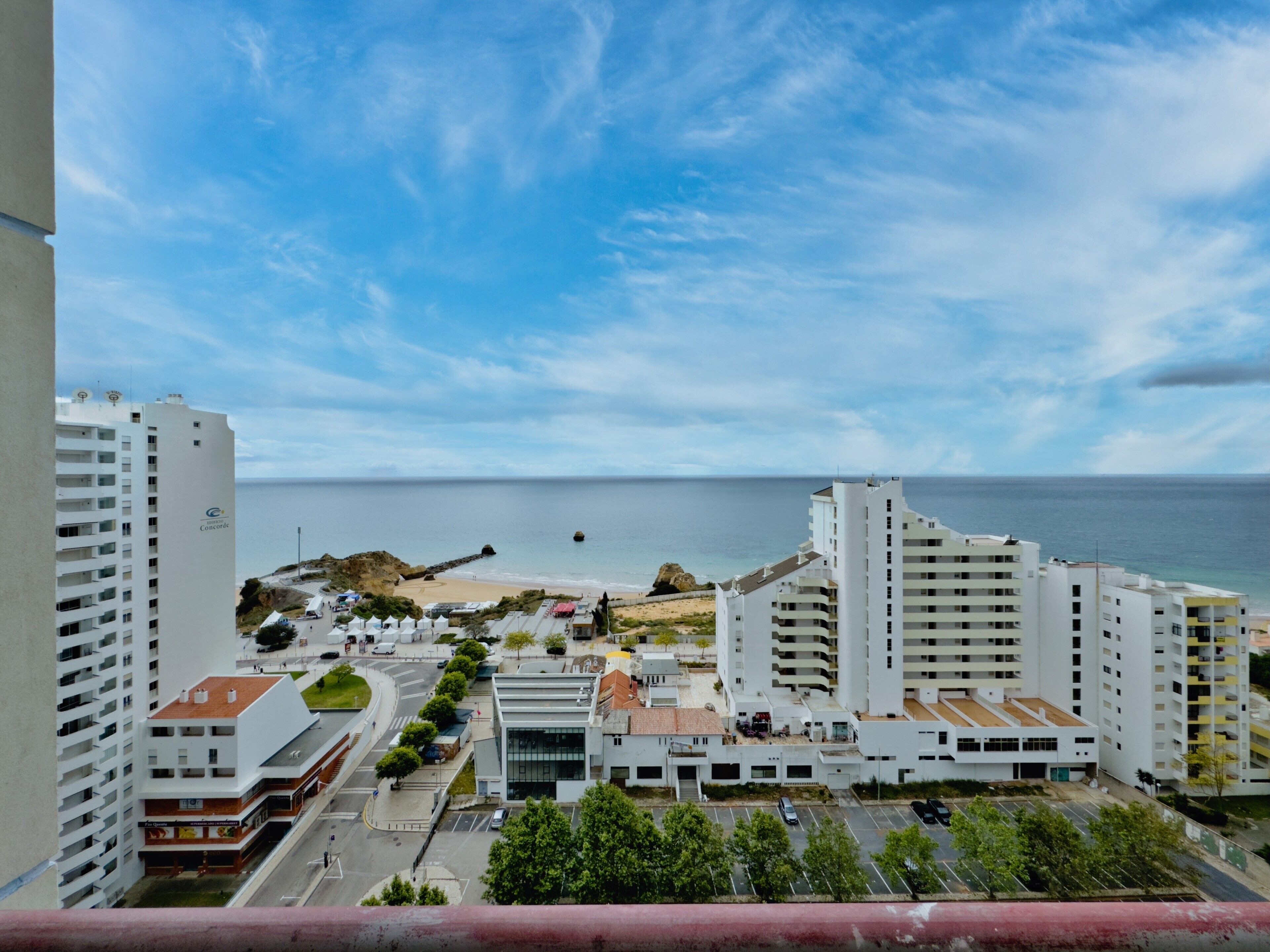 Un paysage urbain côtier avec des bâtiments modernes, une plage et un ciel dégagé.