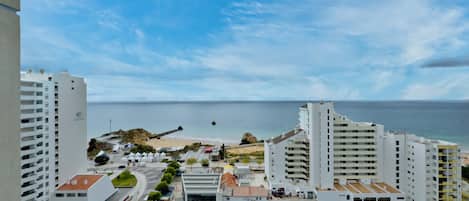 A coastal cityscape with modern buildings, a beach, and a clear sky.
