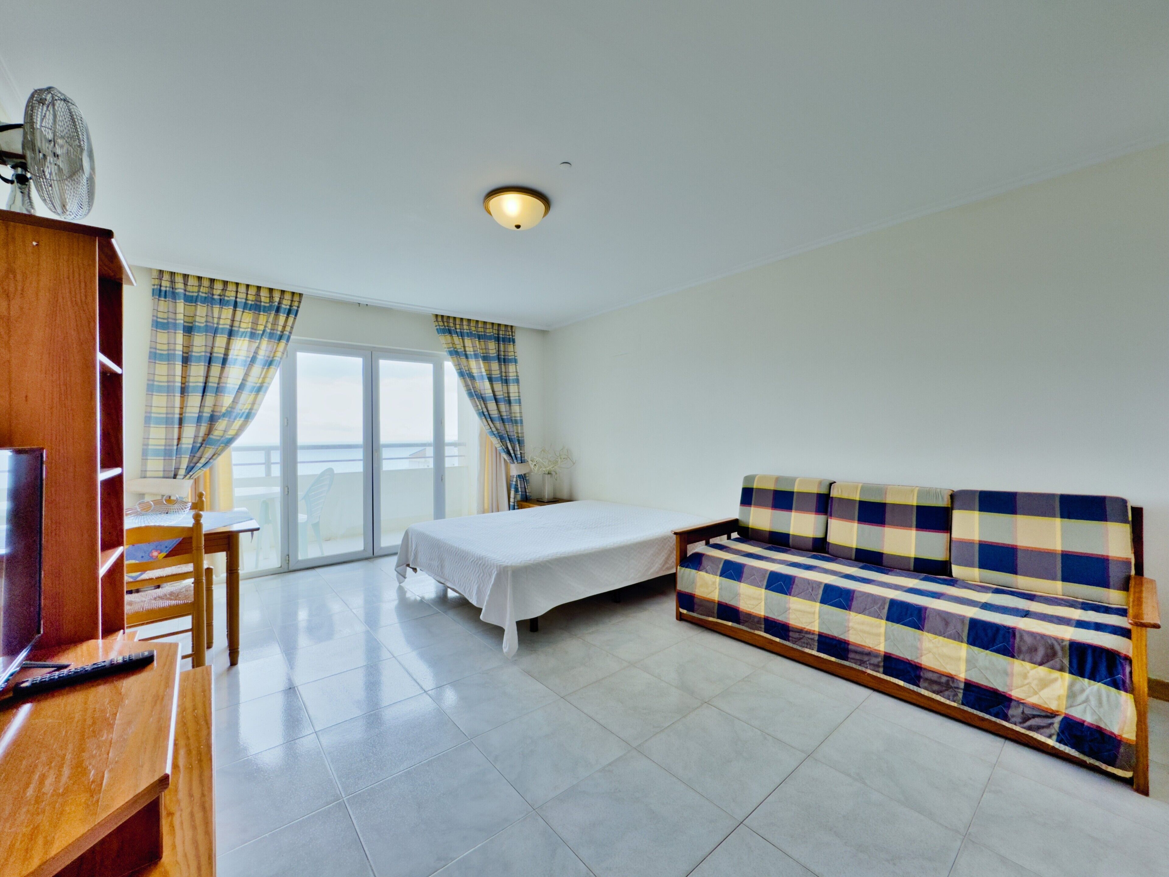 A hotel room with a bed, a sofa, a TV, and a table.