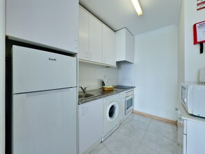 Eine kompakte Küche mit Einbauwaschmaschine, Mikrowelle und Spüle.