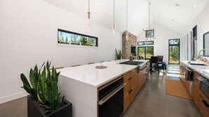 A modern kitchen with a large island, pendant lighting, and a view of the outdoors. - Ridgeline Retreat | Modern 4BR, Big Mountain Views (Tabernash)