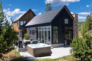 Ein modernes, zweistöckiges Haus mit großem Glasflureingang, einem Whirlpool und Sitzgelegenheiten im Freien.
