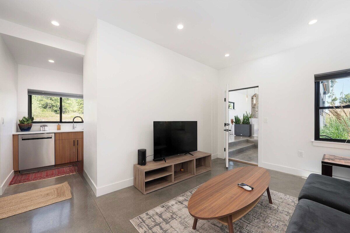 A modern living room with a flat-screen TV, a wooden coffee table, and a grey sofa.