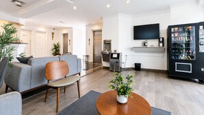 Un salon moderne avec un canapé gris, une table basse en bois et un téléviseur fixé au mur.