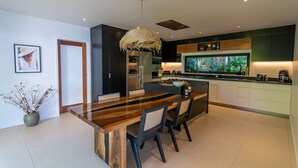 Een moderne keuken met een centraal eiland, inbouwapparatuur en een groot raam met uitzicht op groen.