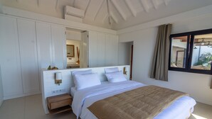 Een slaapkamer met een groot bed, een nachtkastje, een spiegel en een raam met gordijnen.