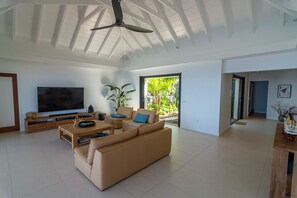 A spacious living room with a flat-screen TV, a sofa, a coffee table, and a ceiling fan. - Villa Mao (2 bedrooms) (Saint Barthélemy)