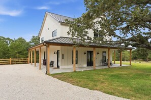 A large, single-story building with a covered porch and a gravel driveway. - Quiet Pond Retreat - Minutes from A&M - Sleeps 12 (College Station)