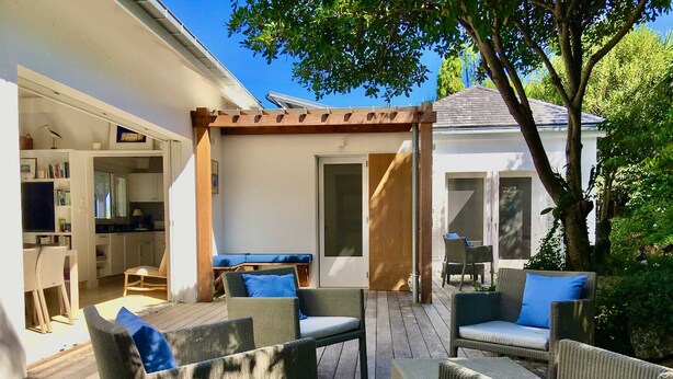 Terraza exterior con mobiliario de mimbre y una estructura de pérgola.
