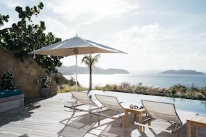 A wooden deck with lounge chairs and a table, overlooking a pool and a scenic view of the sea. - Villa Marie (2 bedrooms) (Saint Barthélemy)