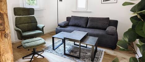 A modern living room with a green chair, a grey sofa, and a small table.