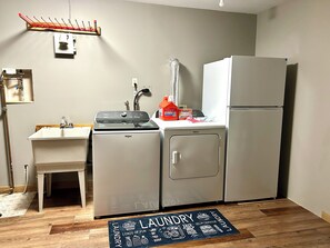 A compact laundry room with a sink, a Whirlpool washer, a dryer, and a refrigerator.