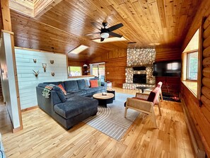 A log cabin interior with a sofa, coffee table, and stone fireplace. - Lakeview Retreat with Buoy (Celista)