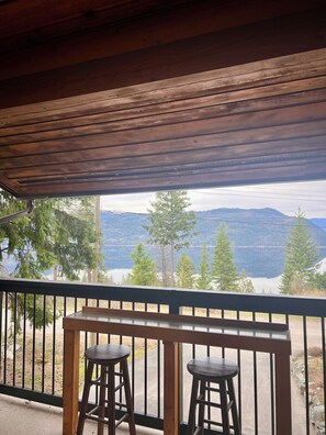 A wooden balcony with two stools, overlooking a lake and mountains. - Lakeview Retreat with Buoy (Celista)