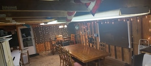 A dining area with a wooden table and chairs, a ceiling fan, and string lights.