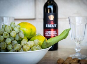 A bowl of green grapes and lemons, a bottle of red wine, and two empty glasses on a kitchen counter. - Studio Apartment with Sea View and Terrace (Postira)