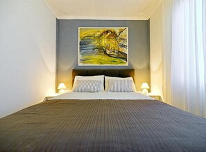 A hotel room with a bed, two bedside lamps, and a painting on the wall. - Studio Apartment with Sea View and Terrace (Postira)