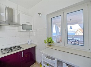 A compact kitchen with a gas stove, a microwave, and a window overlooking a balcony. - One Bedroom Apartment with Terrace an Sea View (Postira)
