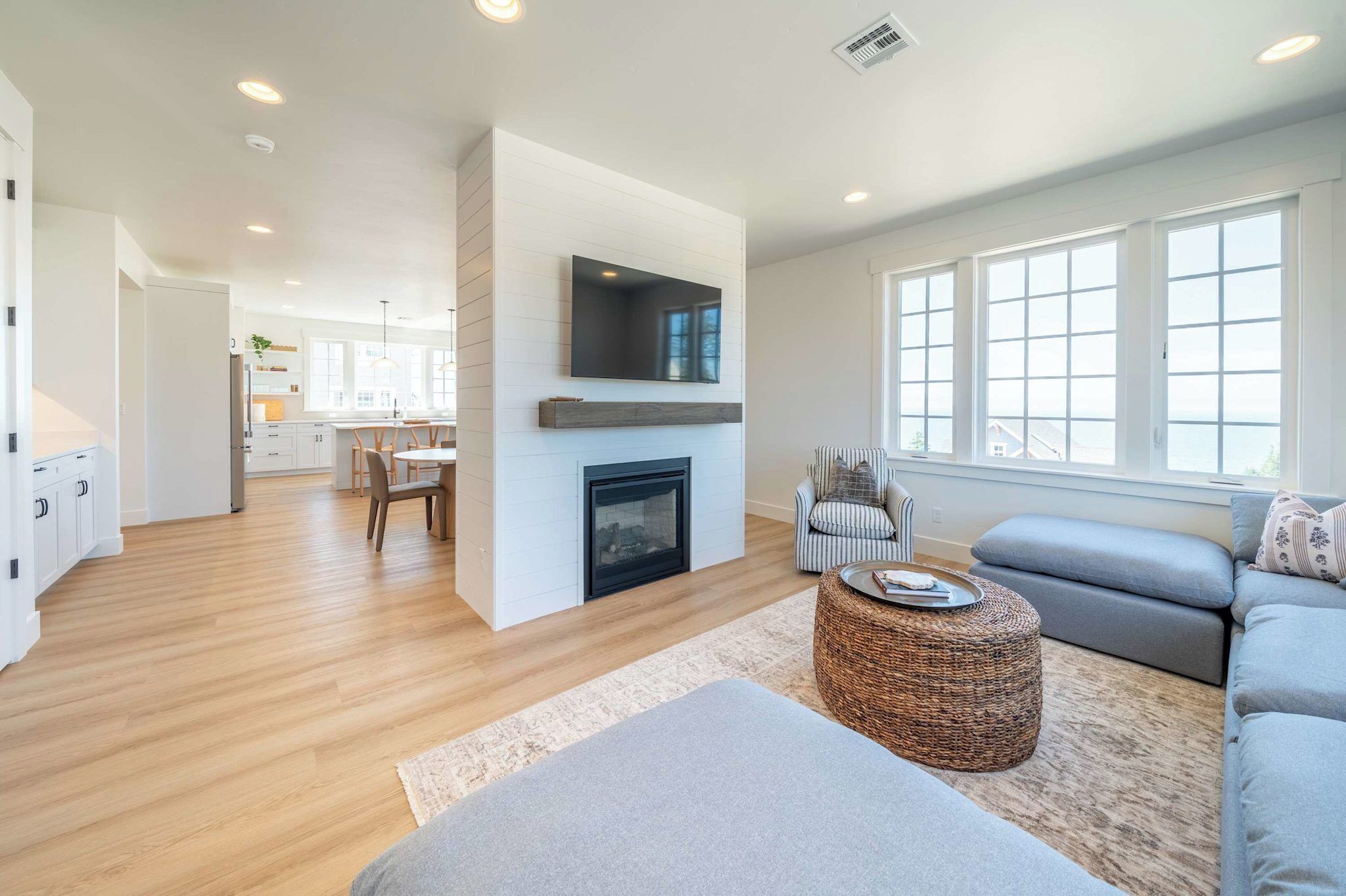 Una sala de estar moderna con chimenea, un televisor montado en la pared y un ventanal con vistas al exterior.
