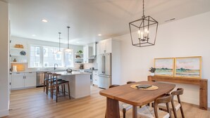 A modern kitchen with white cabinetry, a central island, and pendant lighting. - Seascape Lookout Townhome, Large Kitchen & Pet Friendly (Depoe Bay)