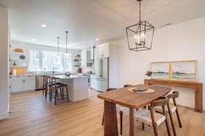 A modern kitchen with white cabinetry, a central island, and pendant lighting. - Seascape Lookout Townhome, Large Kitchen & Pet Friendly (Depoe Bay)