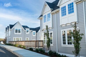 Una hilera de casas adosadas modernas con un estilo arquitectónico uniforme, que incluyen amplias ventanas y un jardín delantero cuidado.