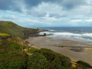 A coastal landscape with a lighthouse, sandy beach, and green hills. - Seascape Lookout Townhome, Large Kitchen & Pet Friendly (Depoe Bay)