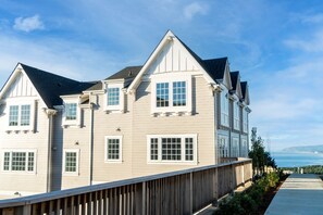 Ein zweistöckiges Haus mit Balkon, einer Holzterrasse und Blick aufs Meer.