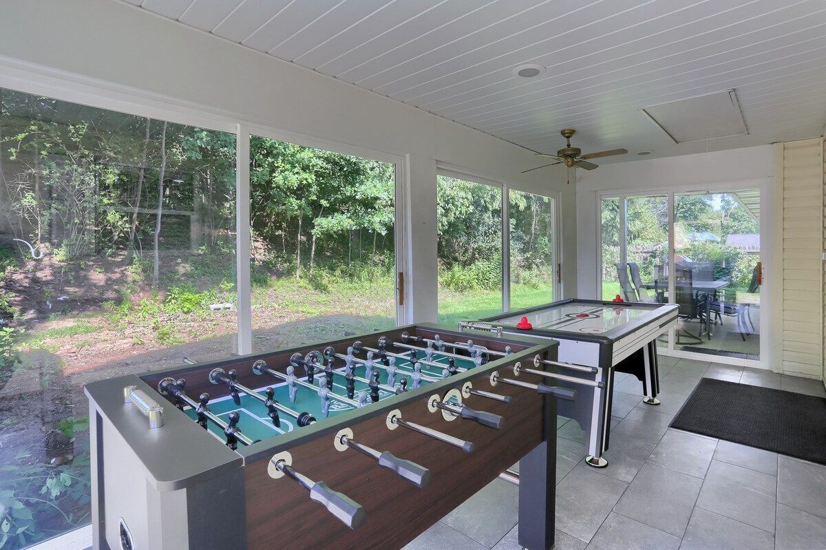 Un espacio recreativo interior con dos mesas de fútbol de mesa y ventanas amplias.