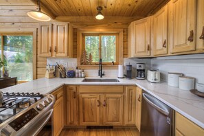 A modern kitchen with wooden cabinets, a stainless steel stove, and a dishwasher. - Beautiful Dog Friendly Cabin in Fairplay (Fairplay)