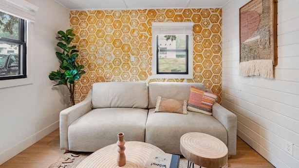 Una sala de estar con pared estampada, un sofá, una mesa de centro y una planta.